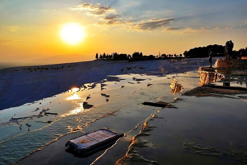 A sunset over a beach with a boardwalk and a sign. 5