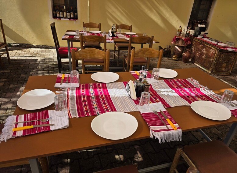 A dining table set with plates, cutlery, and a patterned table runner. 1