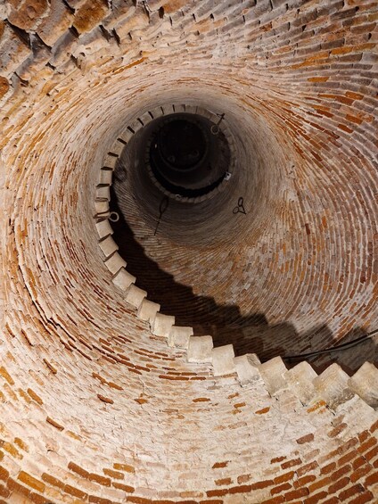 A spiral brick staircase descending into a dark shaft. 3