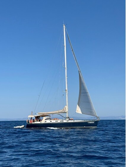 A sailboat with a white sail on a calm sea. 2