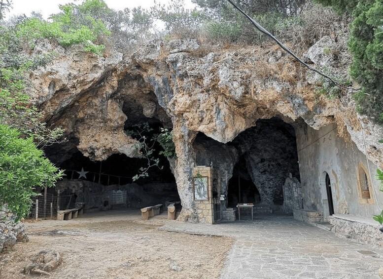 A cave entrance with benches and a table inside. 5