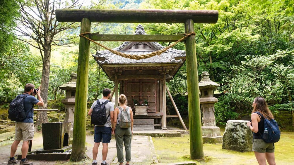 A traditional Japanese torii gate in a forested area with visitors. 2
