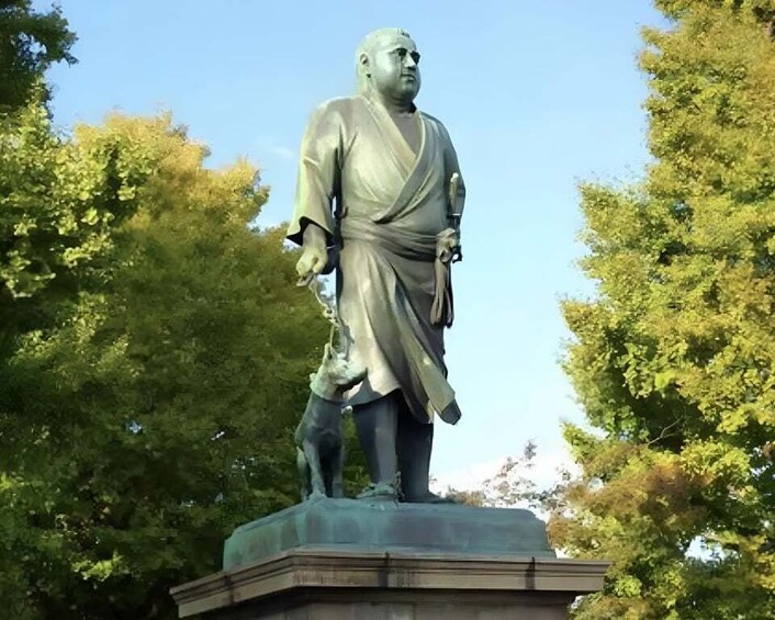 A statue of a man in traditional attire with a dog, surrounded by trees. 1