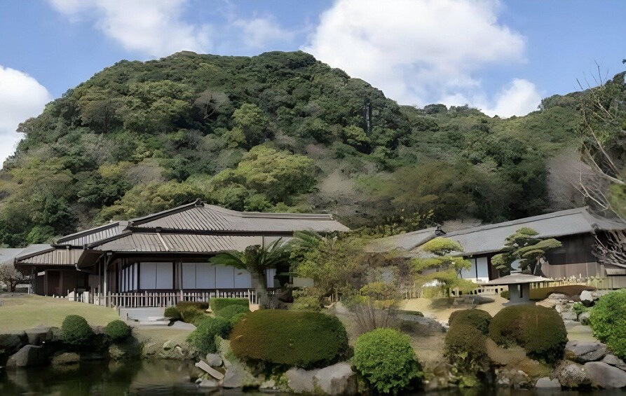 A traditional Japanese building with a pond in the foreground and a mountain in the background. 2