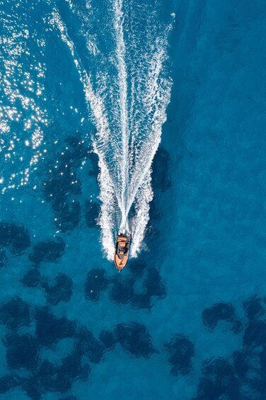 A boat creating a wake in clear blue water. 3