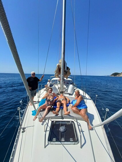 A sailboat with people on deck, calm sea, and clear sky. 2