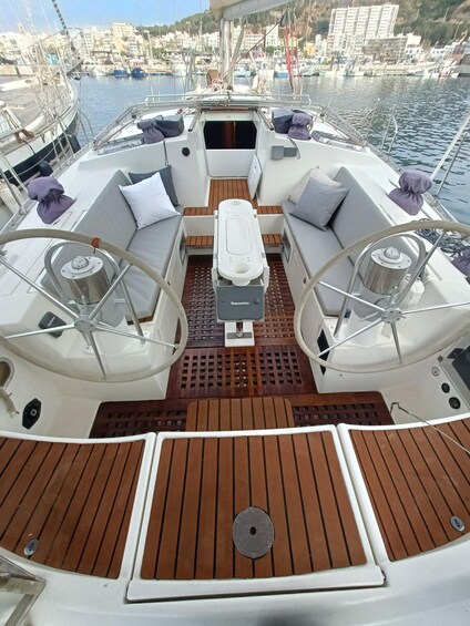 A boat's deck with seating, a central table, and a view of a marina with buildings in the background. 5