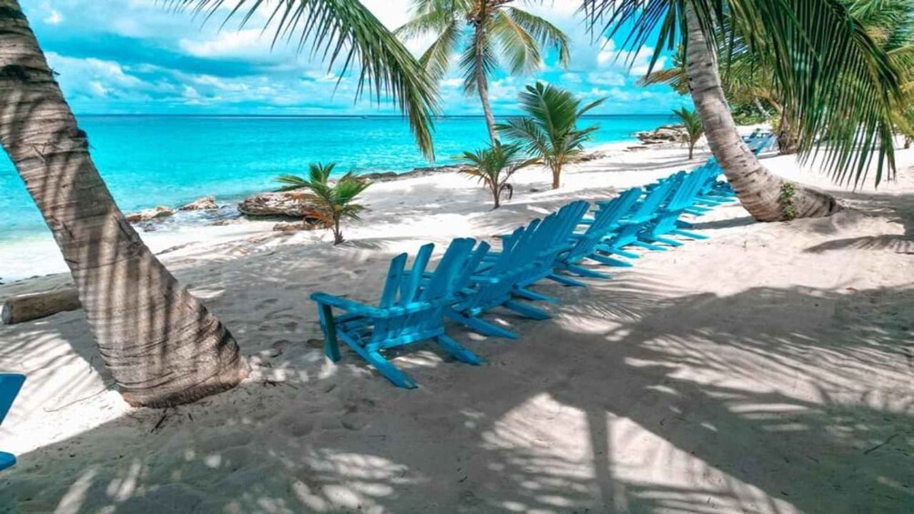 A beach with turquoise water, white sand, and blue lounge chairs. 1