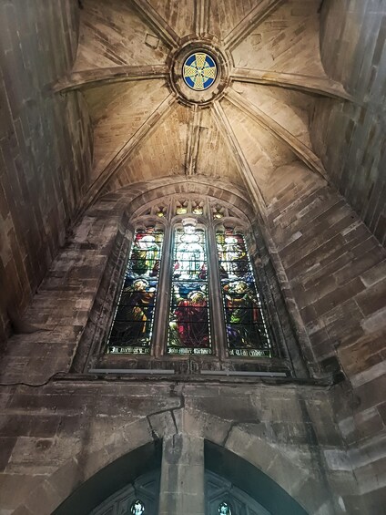 A cathedral interior with Gothic architecture, including pointed arches and a stained glass window. 1