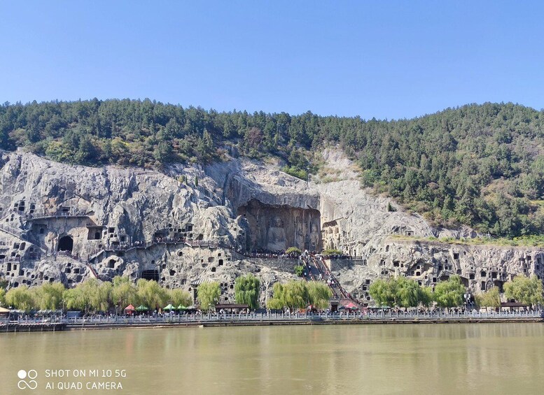 A rock formation with carved dwellings and a river in the foreground. 2