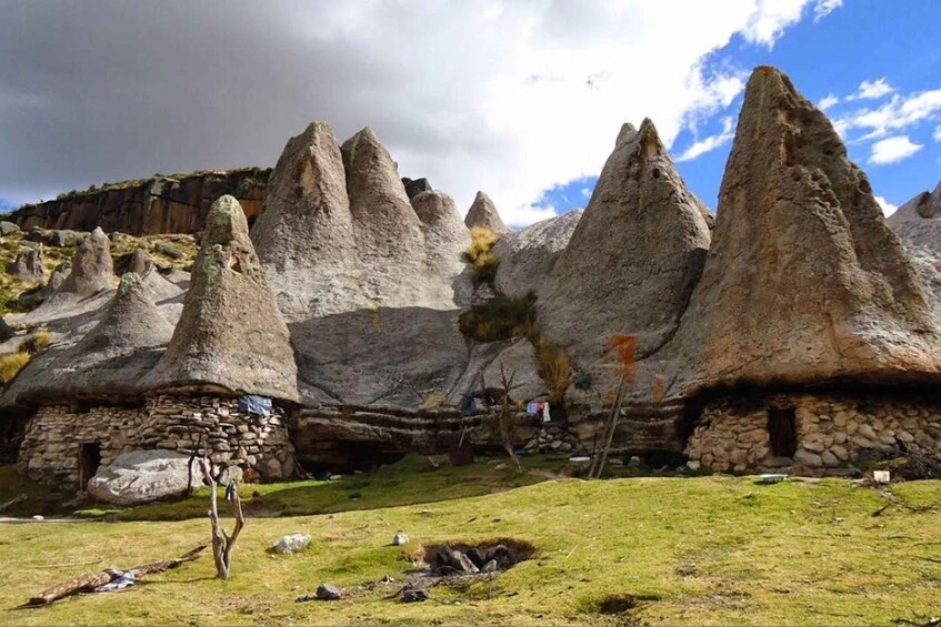 A village with conical stone houses nestled among rocky terrain. 1