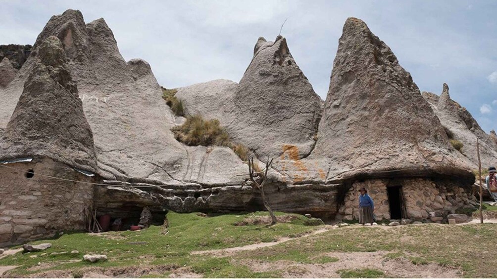 A traditional stone house with a thatched roof, surrounded by a grassy area and rocky formations. 3