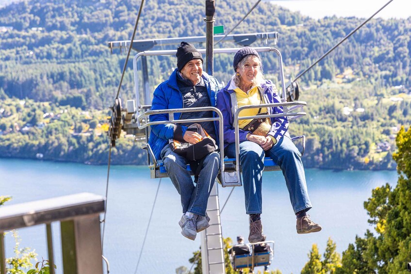 Two people on a cable car over a lake with forested hills in the background. 5