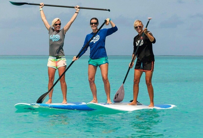 Three people paddleboarding on turquoise water. 1