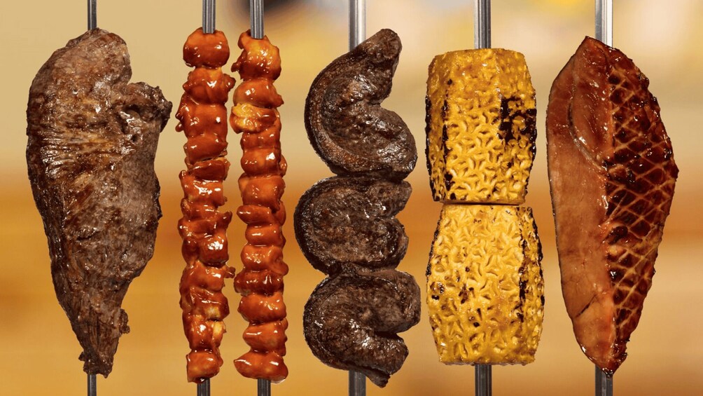 Various meats on skewers, including beef, sausages, and possibly chicken, displayed on a metal rod. 3