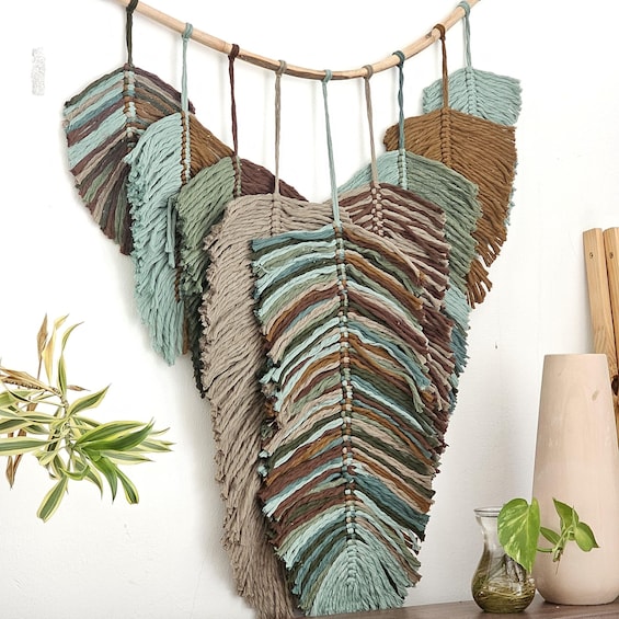 A wall hanging with a heart-shaped design made of braided ropes in various colors. 1
