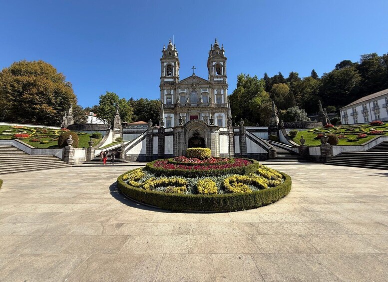 A grand historic building with two towers, surrounded by a formal garden and a large open plaza. 2