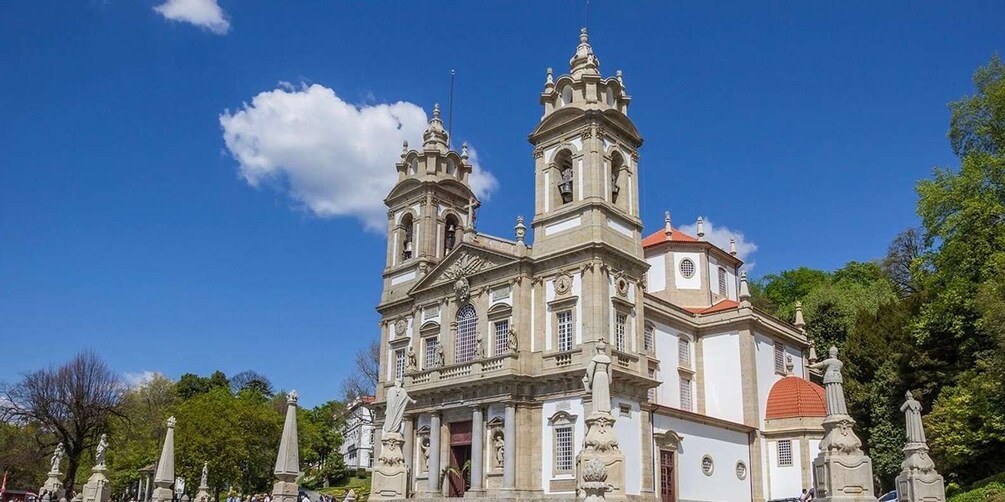 A historic church with two towers and a red dome, surrounded by statues and trees. 3