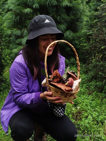 A person in a purple jacket holding a basket with various items. 3