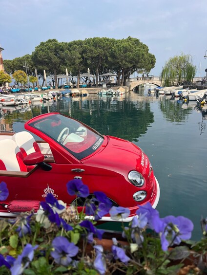 A red boat with a canopy, parked near a calm water body with trees and a bridge in the background. 5