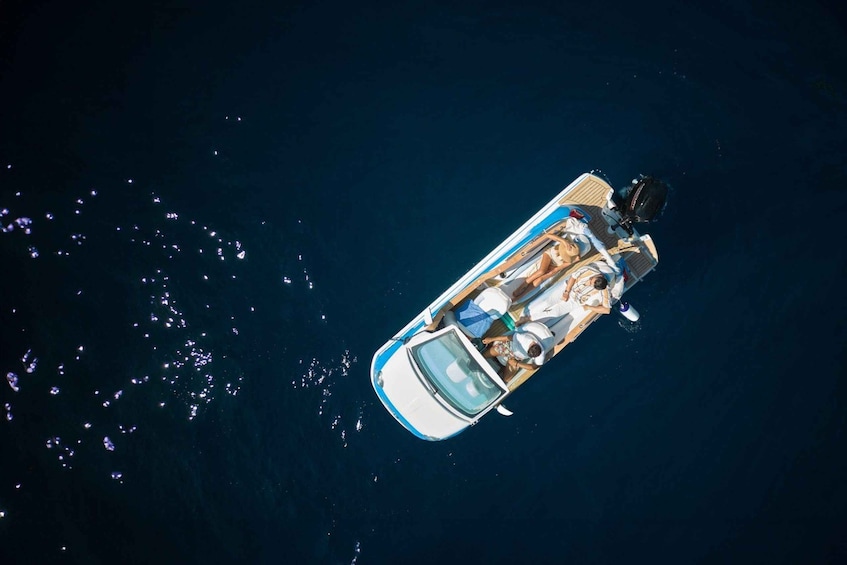 A small boat with two people, one wearing a hat, on a dark blue sea. 1