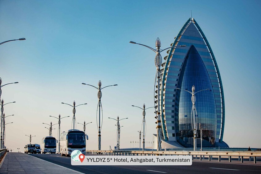 A modern building with a unique shape, a highway with buses, and street lamps. 1