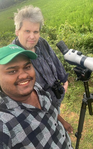 Two people standing in a field with a telescope on a tripod. 5