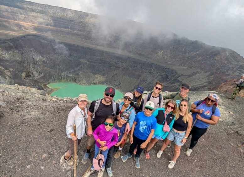 A group of people standing on a rocky terrain with a green lake in the background. 1