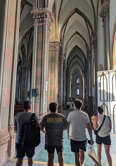 A group of people walking through a cathedral with high arches and columns. 3
