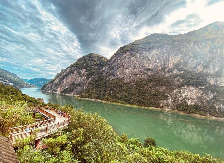 A river with a wooden bridge, lush greenery, and rocky cliffs. 5