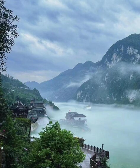 A misty mountain landscape with traditional buildings and a river. 3