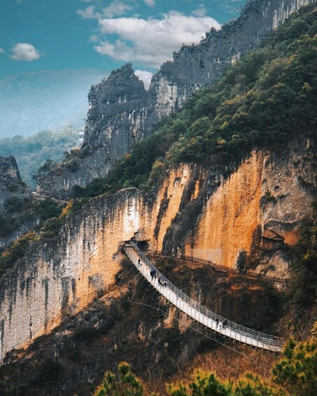 A suspension bridge over a canyon with steep cliffs and dense greenery. 1