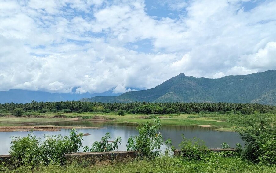 A lake surrounded by greenery and mountains under a cloudy sky. 3