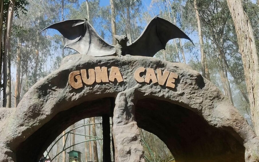 A large rock archway with the words 'GUNA CAVE' and a bat sculpture on top. 4