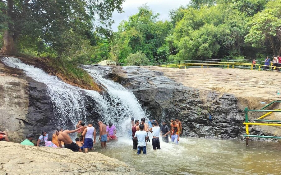 A waterfall, people bathing, and a railing. 1