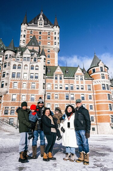 A group of people standing in front of a large, historic building with multiple towers and a prominent clock tower. 4