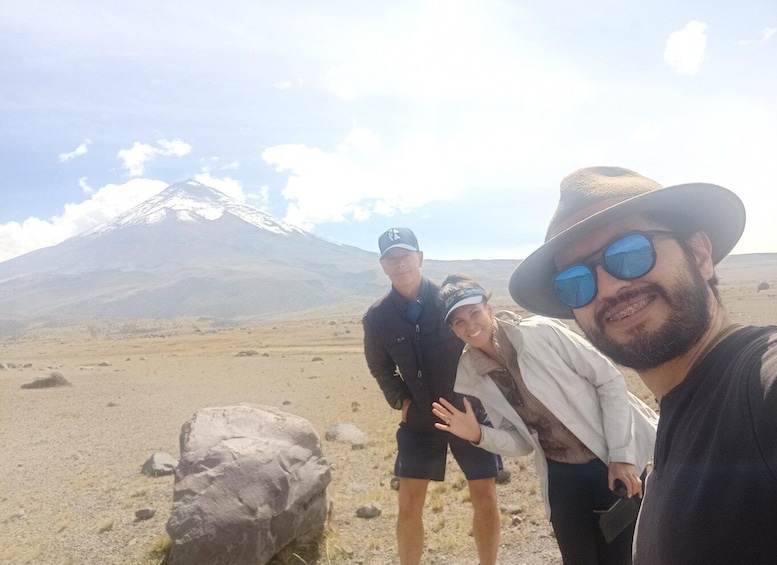 Three people standing in a desert with a mountain in the background. 1