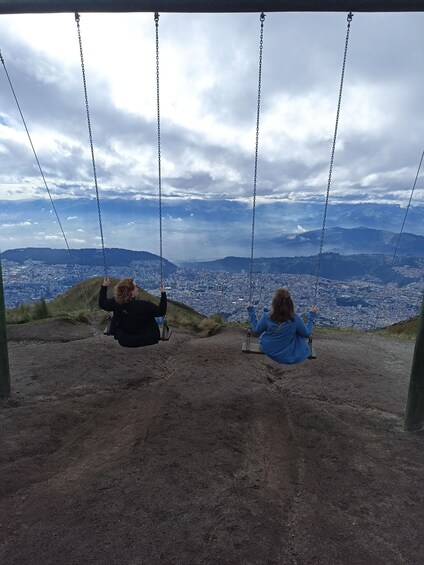 Two people on a swing overlooking a cityscape. 2