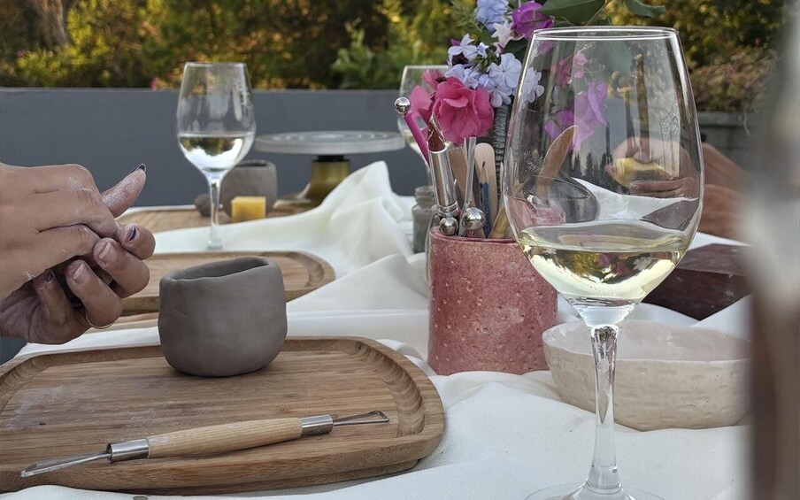 A table with a wine glass, a clay pot, and a wooden board. 5