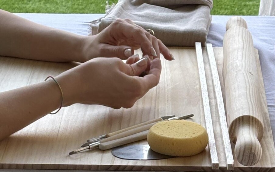A person using a wooden tool, possibly for crafting or woodworking, with a sponge and other tools on a table. 2