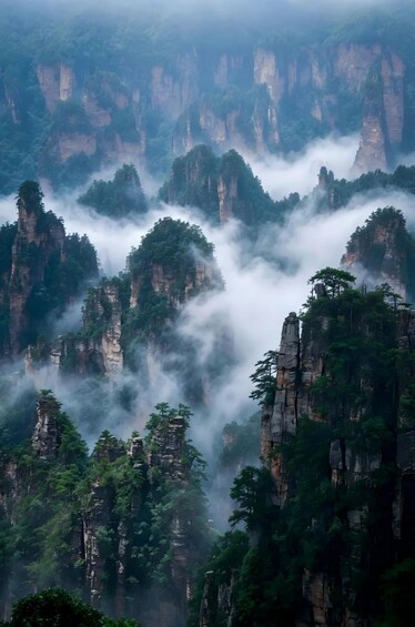 A mountainous landscape with towering rock formations and dense forest. 2