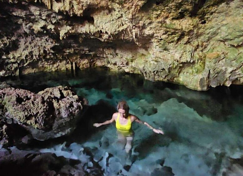 A person swimming in a cave with clear water and rocky walls. 4