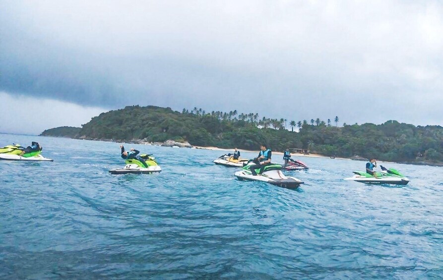A group of jet skis on calm water with a forested island in the background. 4