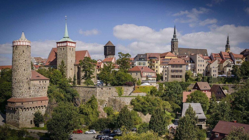 A historic town with stone towers, a church, and residential buildings. 1