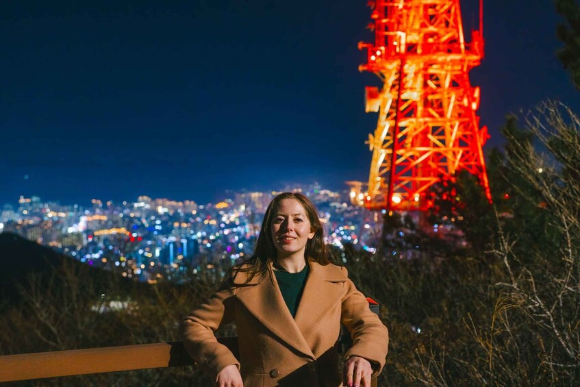 A person standing with a cityscape and a lit tower in the background. 5