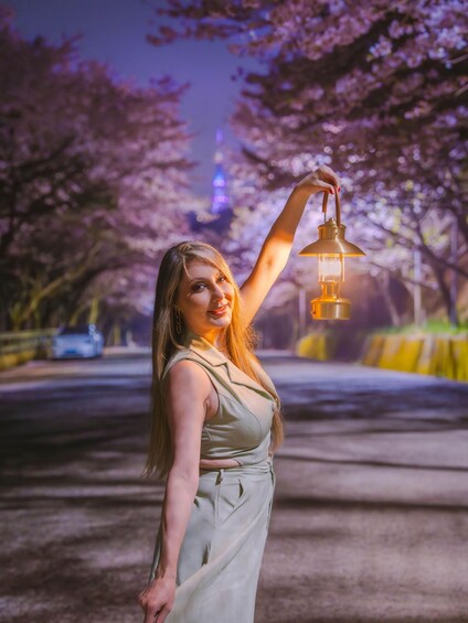 A person holding a lantern in a park with cherry blossoms. 2