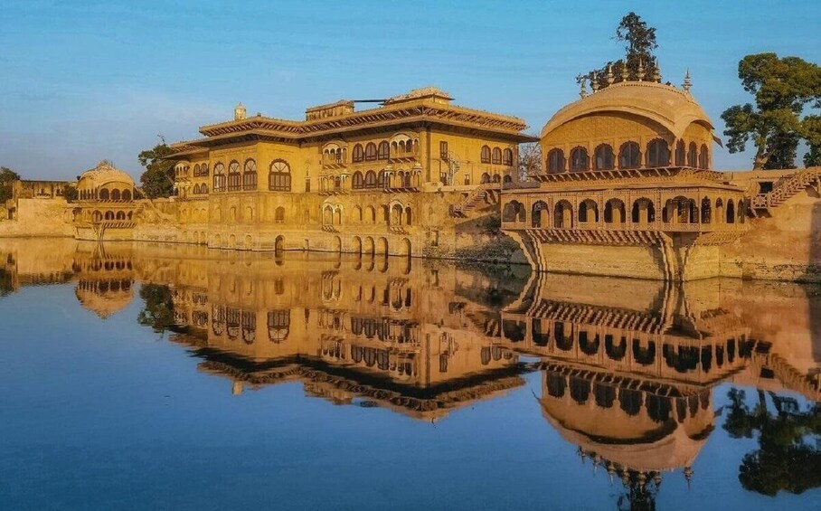 A historic building with arched windows and a dome, reflecting in a calm body of water. 3