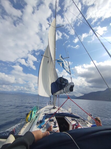 A sailboat on open water with a clear sky and distant land. 4