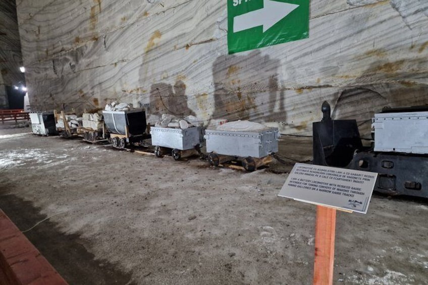 A tunnel with a green directional arrow sign, multiple concrete blocks on wheels, and a warning sign. 5