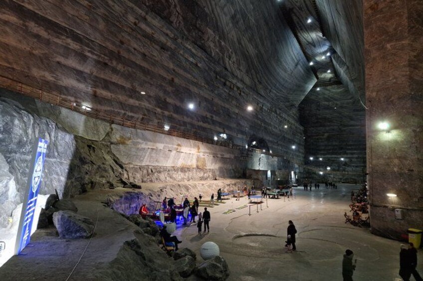 Une grotte artificielle avec des formations rocheuses, un vaste espace ouvert et des personnes qui l’explorent. 1